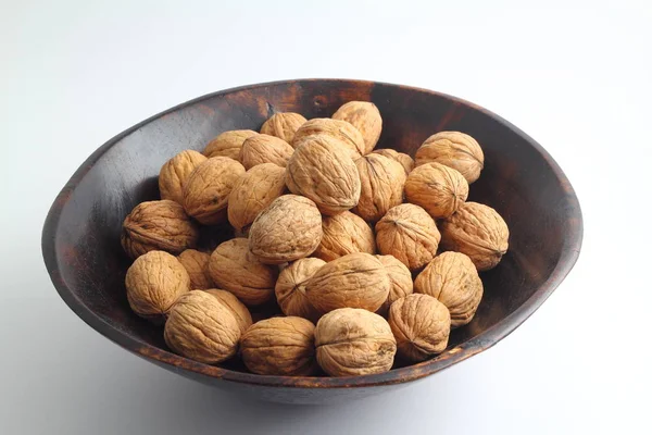 Beyaz arka planda izole edilmiş cevizler. Beyaz arka planda izole edilmiş ceviz yığını. Beyaz arka planda ahşap bir kasede ceviz. Metin için kopyalama alanı olan cevizler.