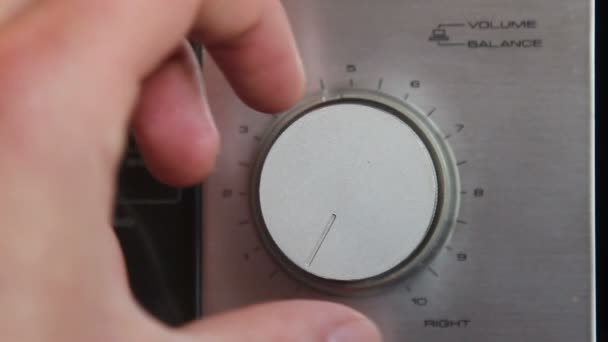 Gros plan de la main tournant un bouton de volume sur l'unité stéréo à la maison