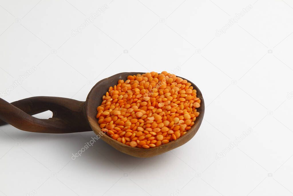 red lentils in wooden spoon isolated on white background. Top view.