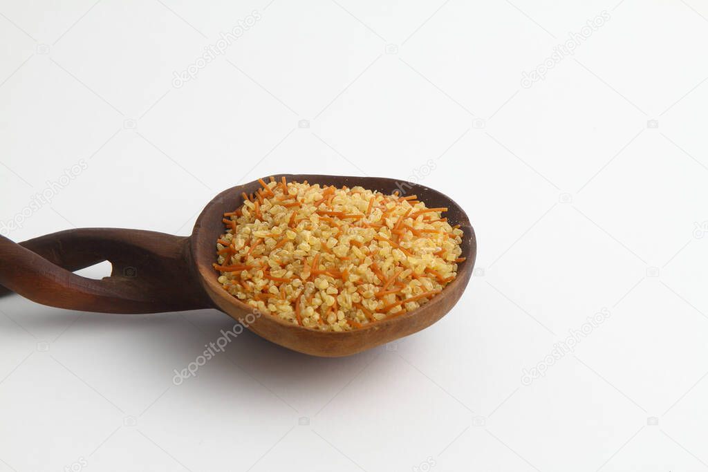 dry bulgur wheat in wooden spoon isolated on white background. top view