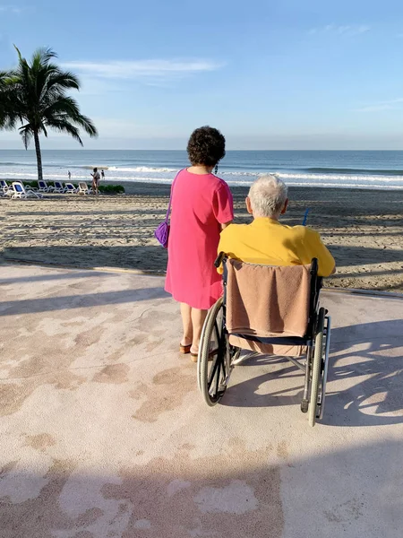 Senior couple with mobility issues looking out over a tropical b — Stock Photo, Image