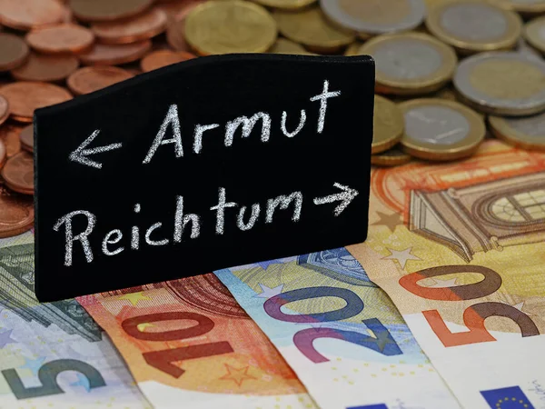 Yoksulluk ve zenginlik anlamına gelen Almanca kelime, avro banknotlarının kara tahtasında, toplumu fakir ve zengin arasında bölen yolu gösteriyor.