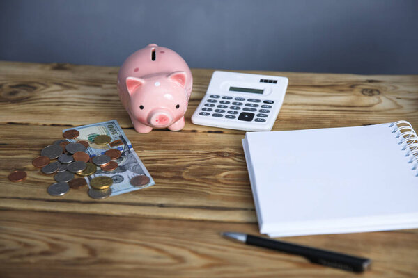 notepad with coins and piggy bank on tabl