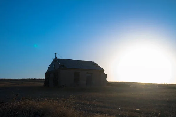 An image of an old run down building in a hay field.