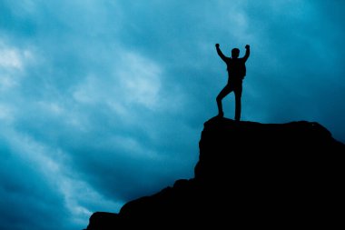 Başarı: Erkek gün batımı silueti kollarını kaldırarak kutluyor.