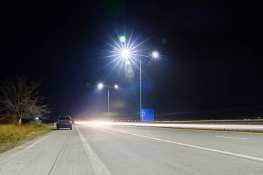 Yanlız bir arabayla aydınlatılmış otoyol.