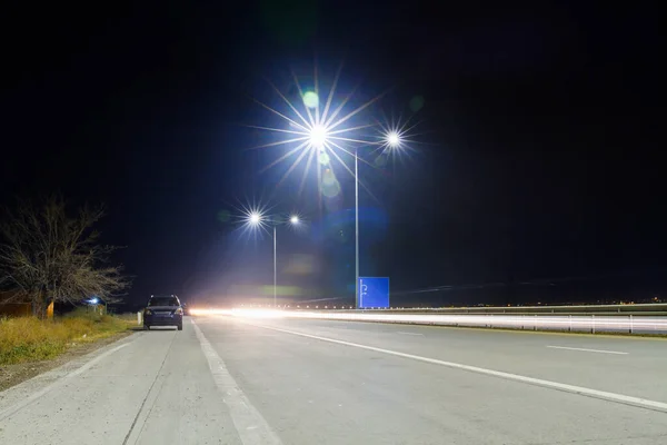 Verlichte Snelweg Met Een Eenzame Auto — Stockfoto