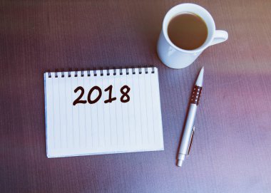 Kahverengi ahşap arka planda defter kalem ve kahve..