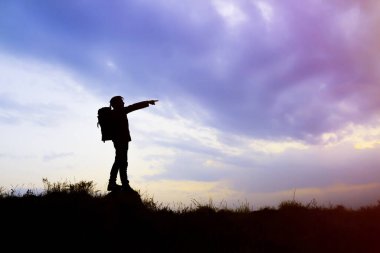 Ayakta duran genç bir adamın silueti dağdaki gece gökyüzünü gösteriyor.. 
