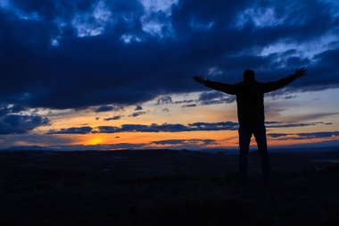 Güzel günbatımında kollarını kaldırmış bir adam