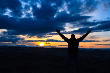 Mutlu çocuk arka planda günbatımında elini gökyüzüne kaldır..