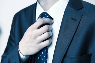 Mavi takım elbiseli genç bir işadamının kravata dokunuşunu yakından çek.. 