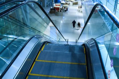 Metroda yürüyen merdiven iniyor, yukarıdan aşağıya bakıyor.