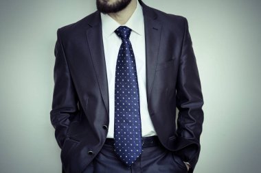 İşadamı elleri ceplerinde duruyor.