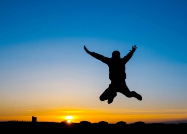 Gün batımında zıplayan bir adamın silueti.