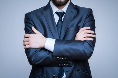Kollarını kavuşturmuş bir takım elbise giyen zarif erkek modelin yakın plan portresi..