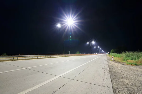 Geceleri sokak lambaları olan boş kırsal yol. 