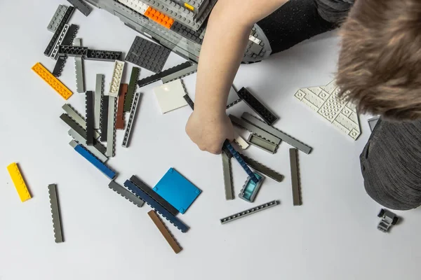 Der Junge sammelt aus den Details des Konstrukteurs Lego-Schiff — Stockfoto
