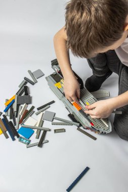 Çocuk renkli parçalardan bir müteahhit topluyor.