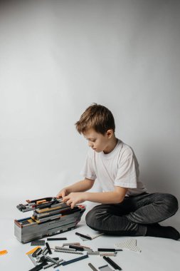 Çocuk renkli parçalardan bir müteahhit topluyor.