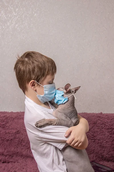 Ein Junge und eine glatzköpfige Katze in medizinischen Masken schützen sich vor Virus, Coronavirus, Epidemie, Luftverschmutzung — Stockfoto