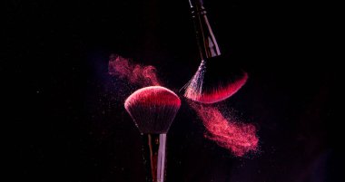 Parlak bir toz paletinde kozmetik fırçalar. Makyaj altında renkli patlama.