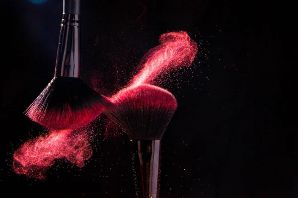 Cosmetic brushes in a bright palette of powder. Colorful explosion under makeup.