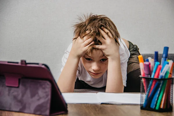 A boy sits at home in isolation and learns online