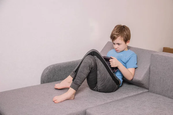 Happy Cheerful Boy Playing Tablet While Sitting Sofa While Isolated — Stock Photo, Image