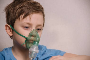 Çocuk öksürükten, zatürreeden, koronavirüsten ve bronşitten kurtulmak için nebulizatörle solunum yapıyor.