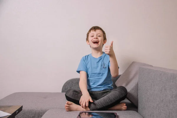 Feliz Niño Alegre Jugando Una Tableta Mientras Está Sentado Sofá — Foto de Stock