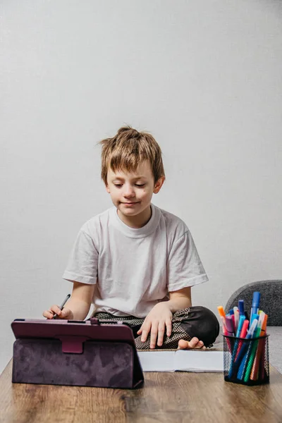 Ein Junge Sitzt Isoliert Hause Und Lernt Online lizenzfreie Stockfotos