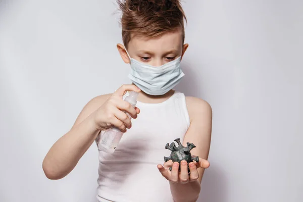 El tipo de la máscara sostiene en su mano el virus coronavirus tratando de matarlo con un antiséptico o desinfectante. — Foto de Stock