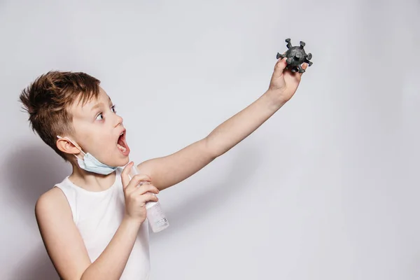 Der Mann in der Maske hält das Coronavirus in der Hand, das versucht, ihn mit einem Antiseptikum oder Desinfektionsmittel zu töten — Stockfoto