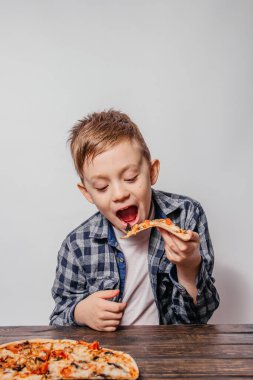 Büyük bir zevkle bir dilim pizza yiyor.