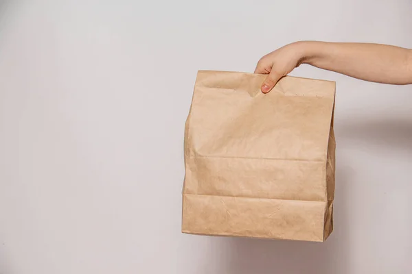 Brown craft paper bag for the removal or delivery of goods and food in hands on a white background. Place for advertising. delivery service concept — Stock Photo, Image