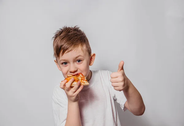 Der Typ mit großem Vergnügen isst ein Stück Pizza und zeigt wie auf weißem Hintergrund Stockfoto