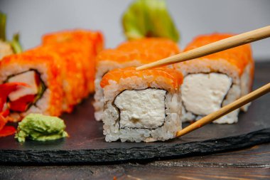Güzel ve lezzetli, taştan bir tahtanın üzerinde çeşitli suşi ruloları.