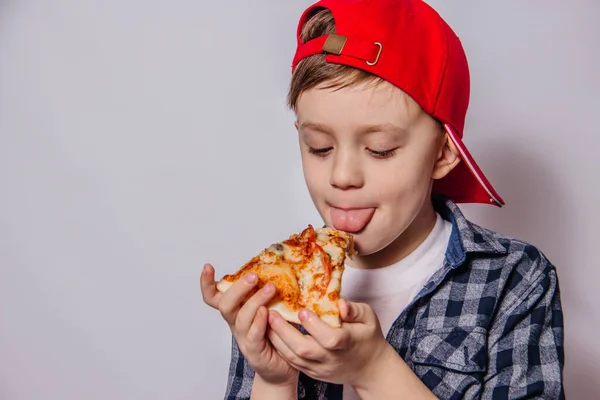 The guy is eating a slice of pizza while holding her hands.