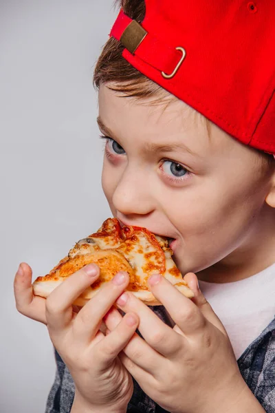 The guy is eating a slice of pizza while holding her hands.