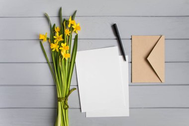 Mektup, zarf ve Nergis gri arka plan üzerinde. Romantik tatil kavramı, üstten görünüm, düz yatıyordu