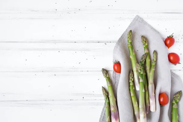 Ingredienti per una sana colazione: asparagi freschi, pomodori sul tavolo bianco. Composizione in stile rustico. Posa piatta, vista dall'alto — Foto Stock