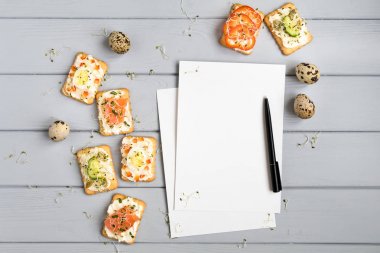 Tarifi kitabı sayfası ve krem peynir ve çeşitli soslar ile kraker. Gri masada meze. Üstten Görünüm, düz yatıyordu