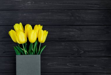 Parlak sarı laleler Eko kağıt kutusunda siyah vintage ahşap masa. Düz yatıyordu, en iyi görünümü