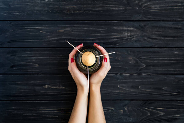 Woman hands holding avocado seed in glass bottle with water. Flat lay, top view