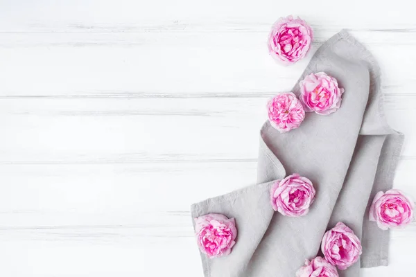 Belles roses roses sur nappe en tissu de lin gris. Cadre décoratif sur table en bois vintage blanc. Couché plat, vue du dessus — Photo