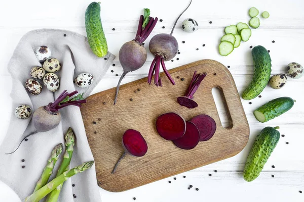 Barbabietola affettata su tagliere di legno, circondata da verdure. Posa piatta, vista dall'alto — Foto Stock