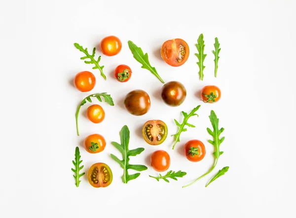 Cherry tomatoes and rocket salad leaves pattern on white background. Flat lay