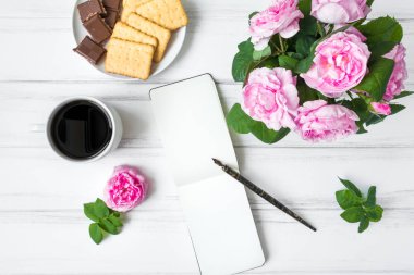 Kahve, sketchbook ve gül beyaz vintage ahşap masa karşı rahat kompozisyon Kupası ile. Düz yatıyordu, en iyi görünümü
