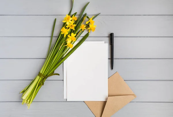 Carta, envelope e narcisos sobre fundo cinzento. Conceito de férias românticas, vista superior, flat lay — Fotografia de Stock